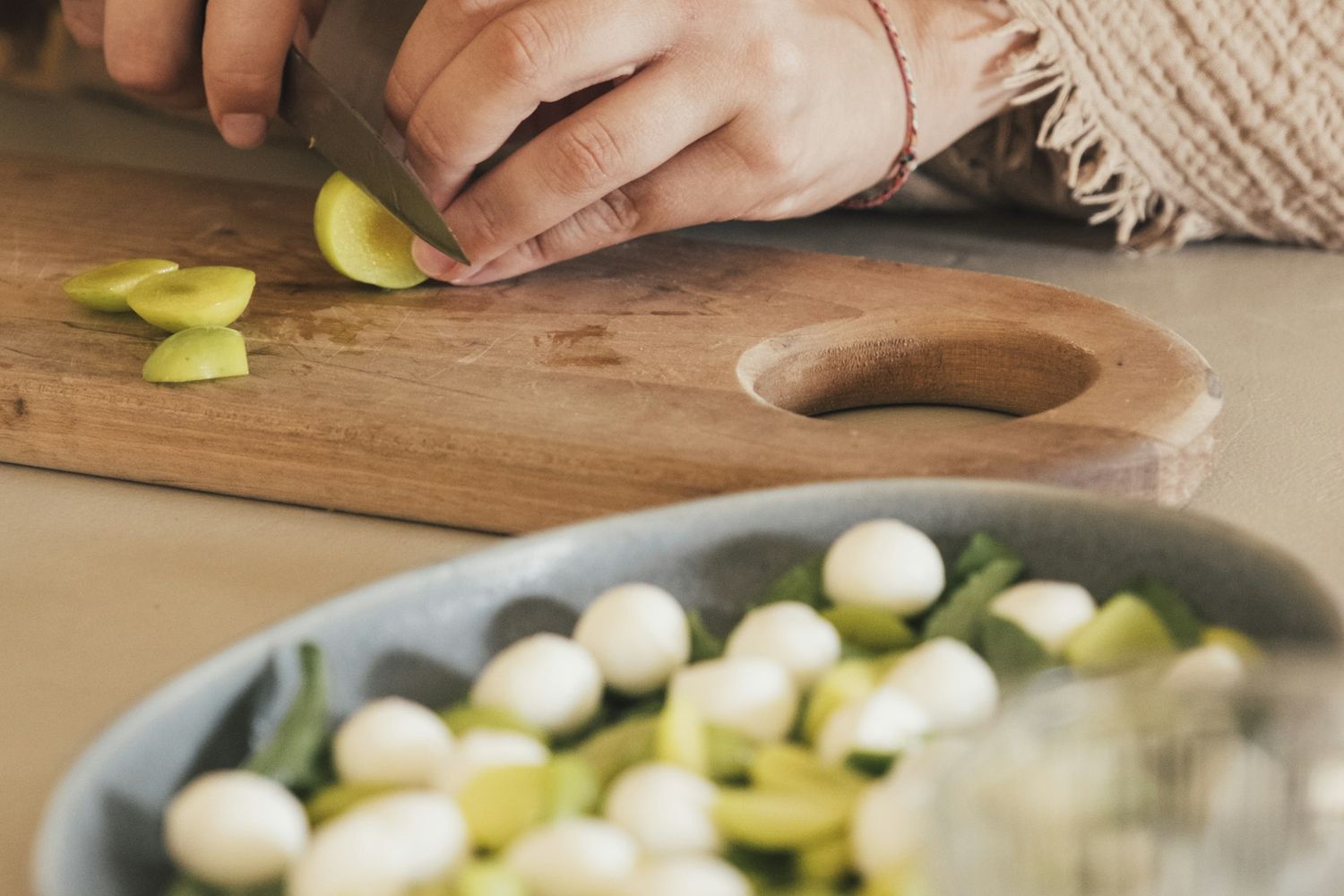 Hands slicing fresh produce for a salad
