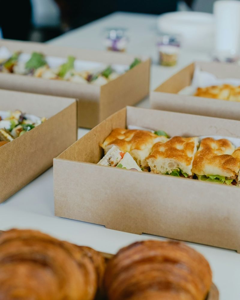 Boxed lunches of sandwiches and pastries laid out on a table