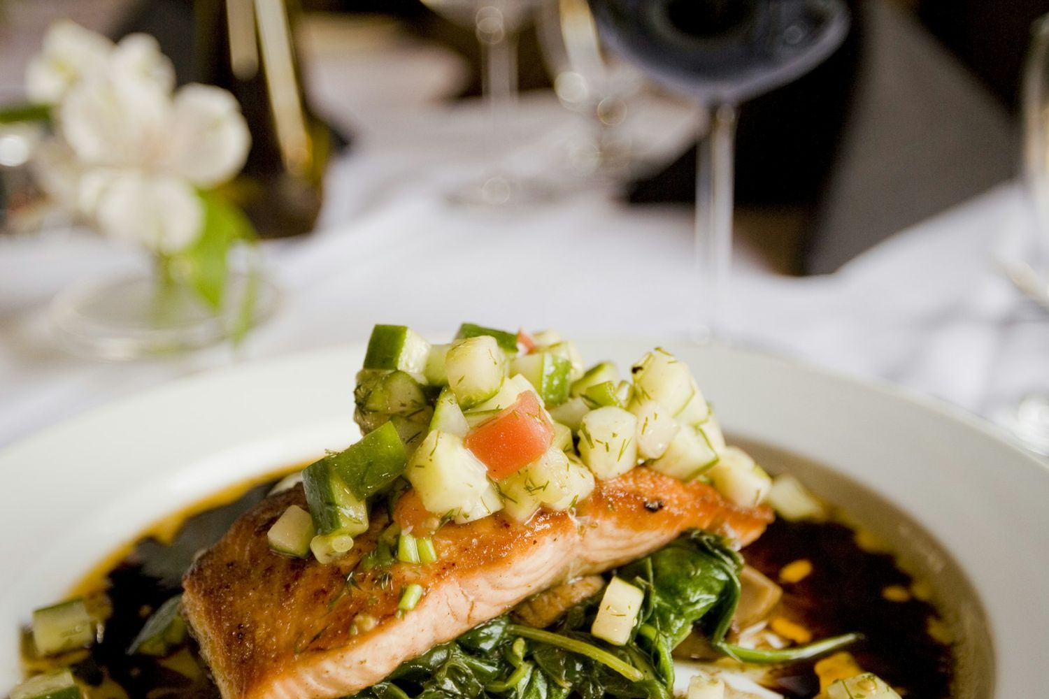 A plated salmon main course with a glass of red wine